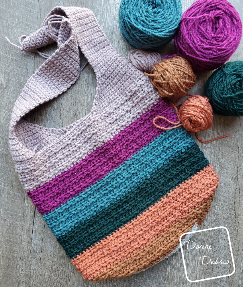 [Image description] Striped Alix Bag lays flat on the group, at an angle, with caked up yarn on the top right of the photo.