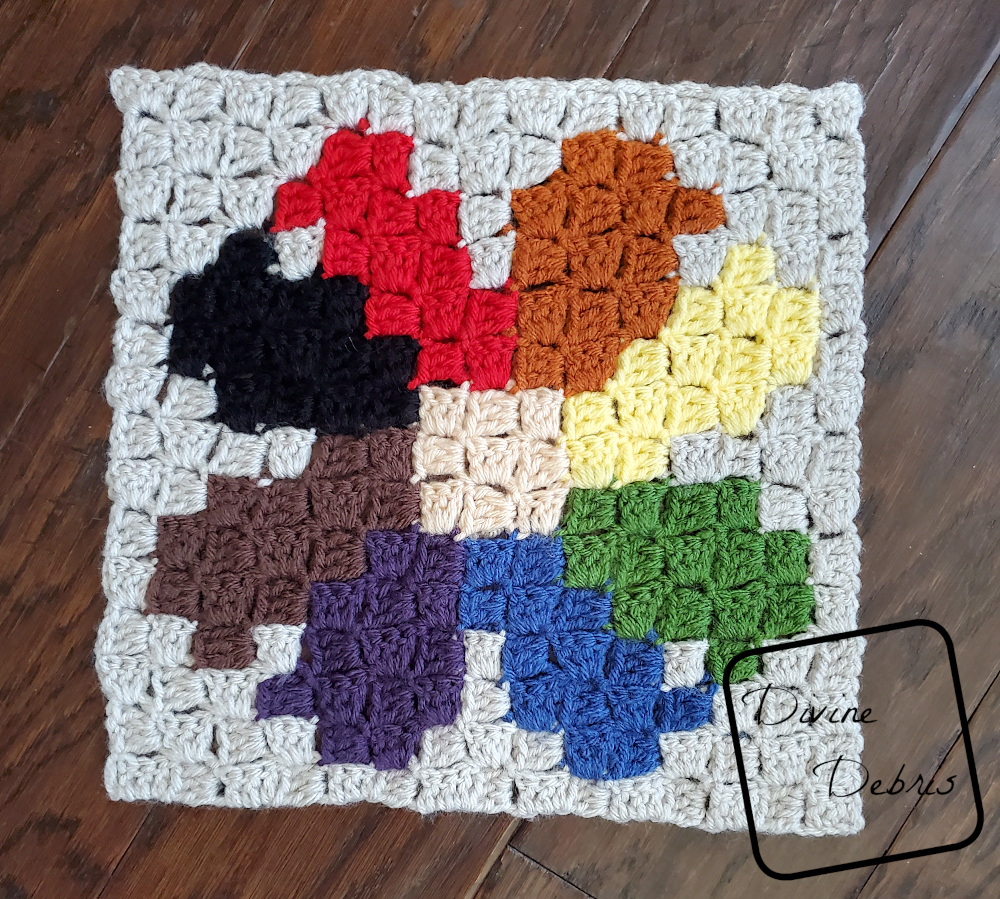 [Image description] the C2C Daisy Afghan Square lays on a wood background .