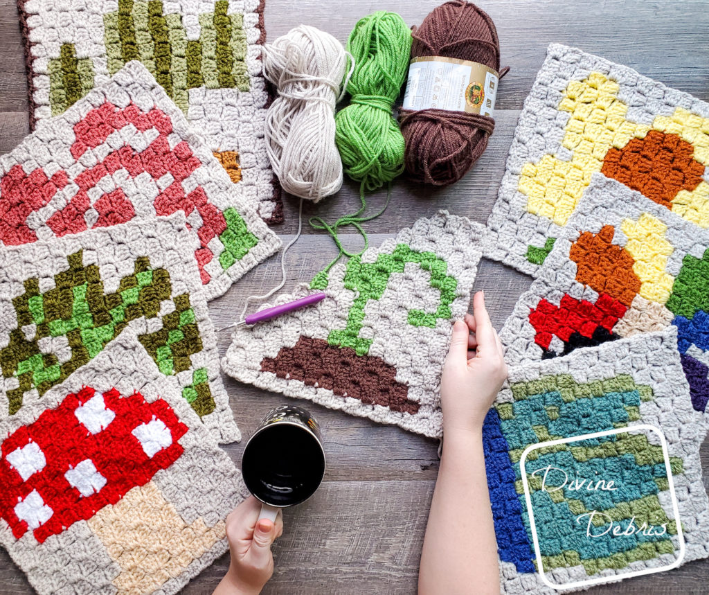 [Image description] Divine Debris's 2021 Plants CAL squares, 4 squares on the left and 3 on the right with a new half-finished square in the middle that's being held on the right by a white woman's hand.