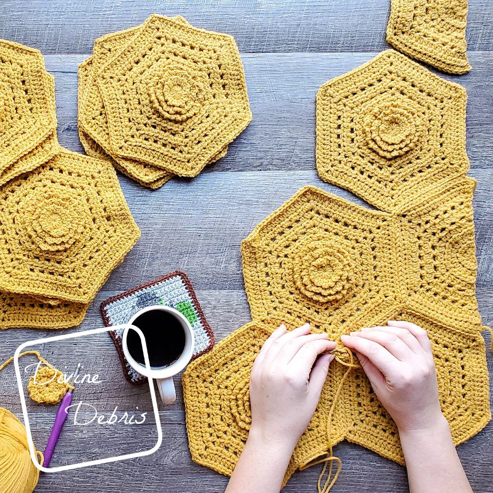 [Image description] A top down view of two white woman's hands seaming together the mustard colored hexagons from the Florence Hexagon Blanket. A cup of coffee sits to the middle left of the hands and a pile of hexagons sits to the left top of the photo