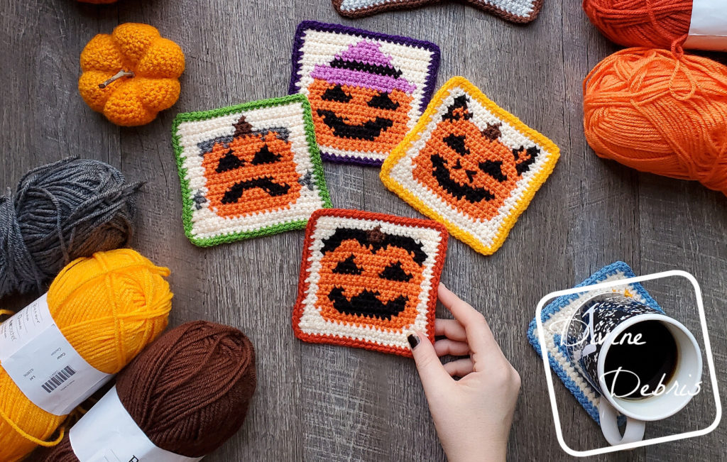 [Image description] Halloween Pumpkin Coasters crochet patterns laying flat on a wood-grain background, a white woman's hand holds the bottom coaster and 3 skeins of yarn are on the bottom left and 2 skeins are on the top right. 