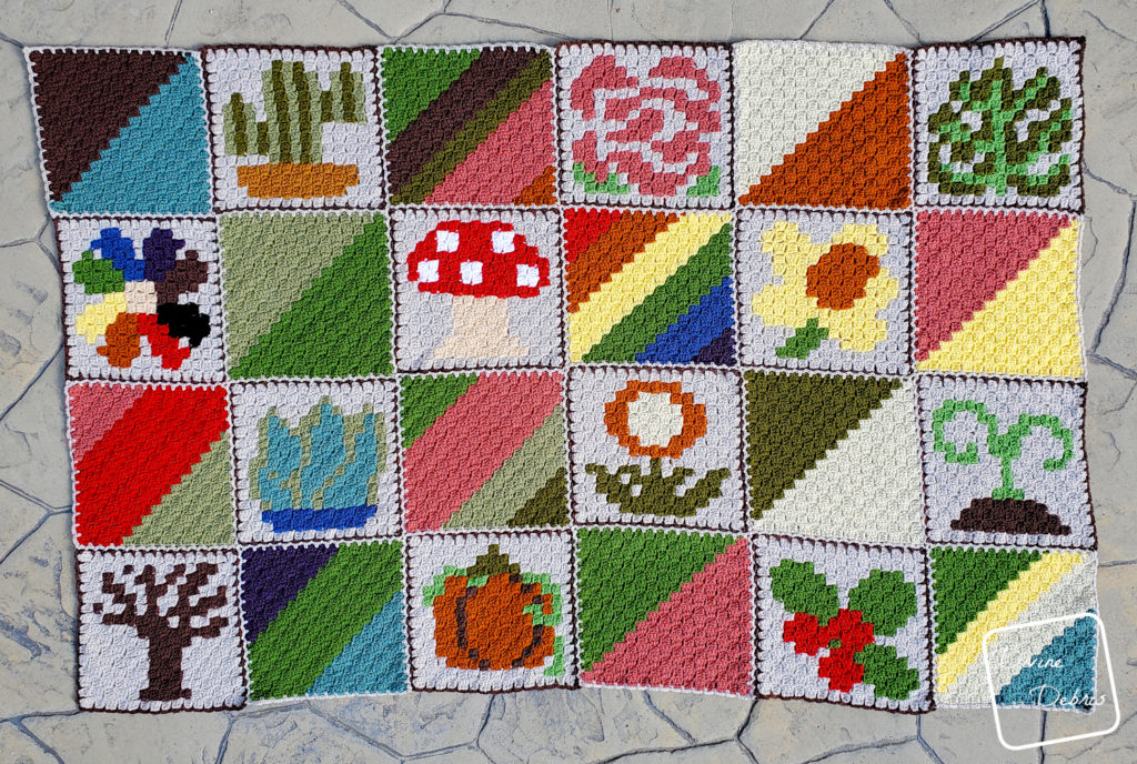 [Image description] The finished C2C Plants Afghan Squares blanket lays flat on a cement background with 12 other colorful squares to make a 6 x 4 blanket.