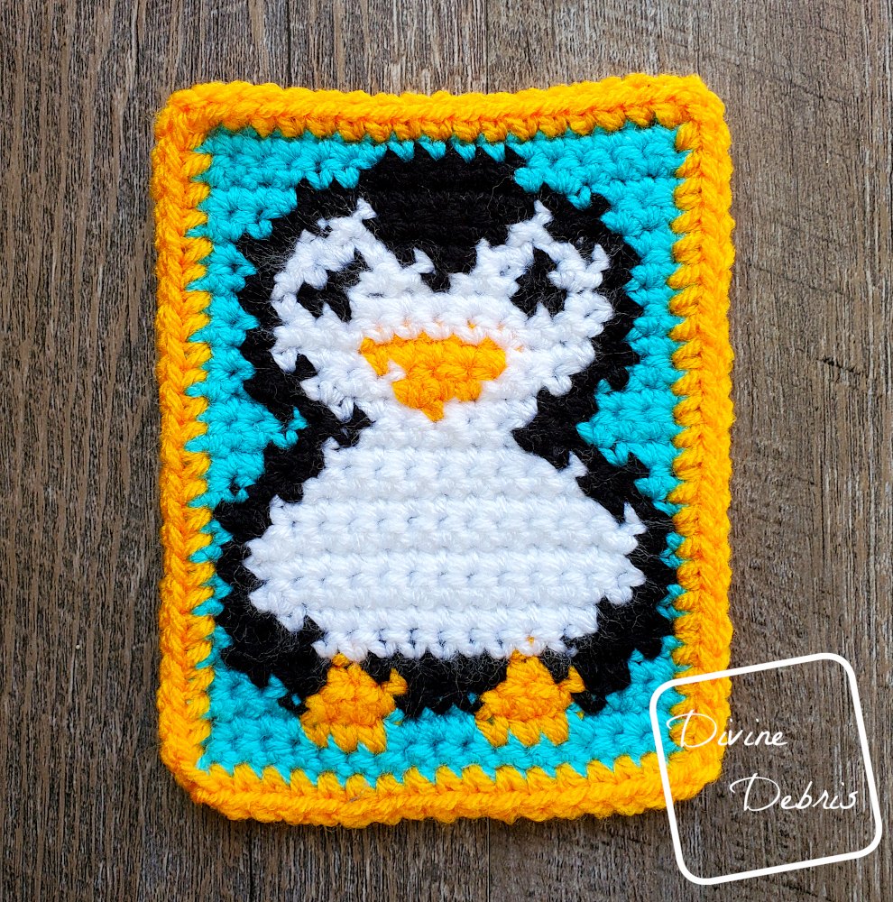 [Image description] A close up of the Cute Penguin Coaster crochet pattern, on a wood grain background.