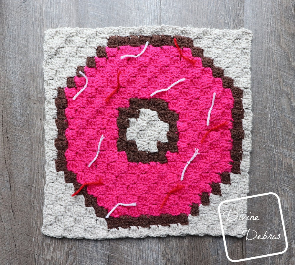 {Image description] the C2C Donut Afghan Square lays in the center of a fake wood background