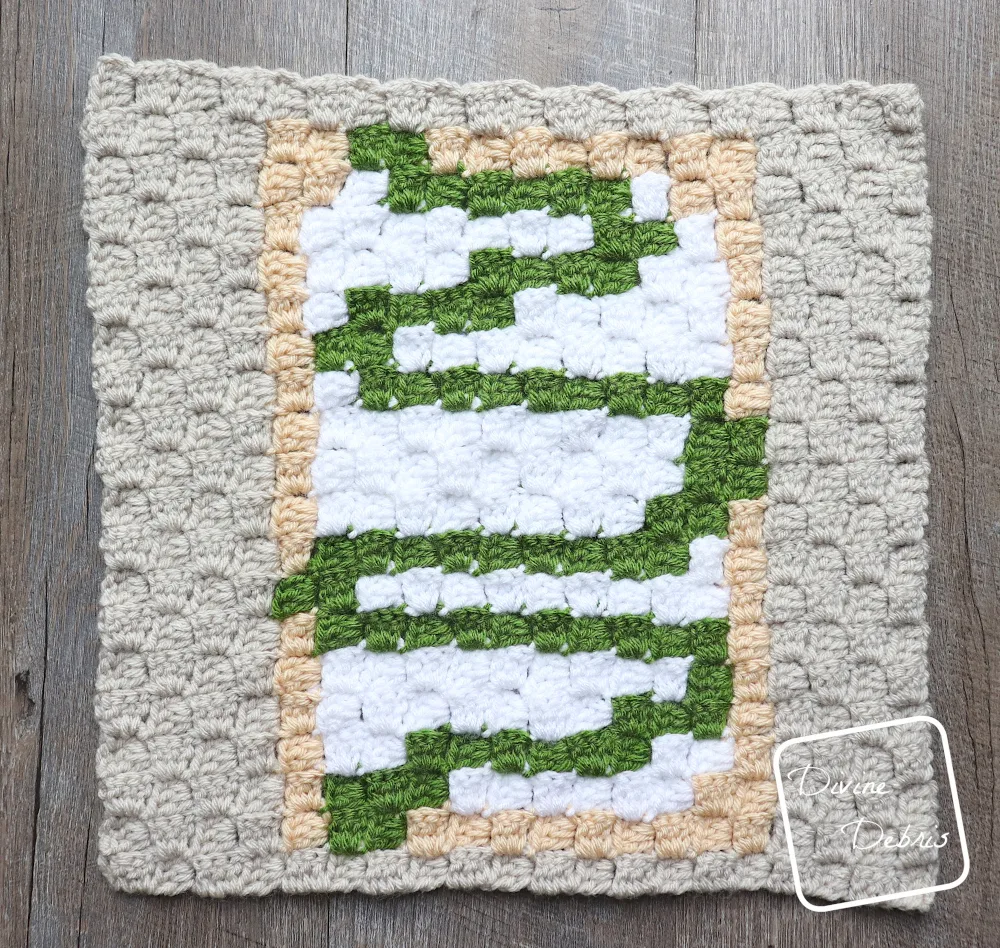 [Image description] A top down photo of the C2C Toaster Pastry Afghan Square on a fake wood background.