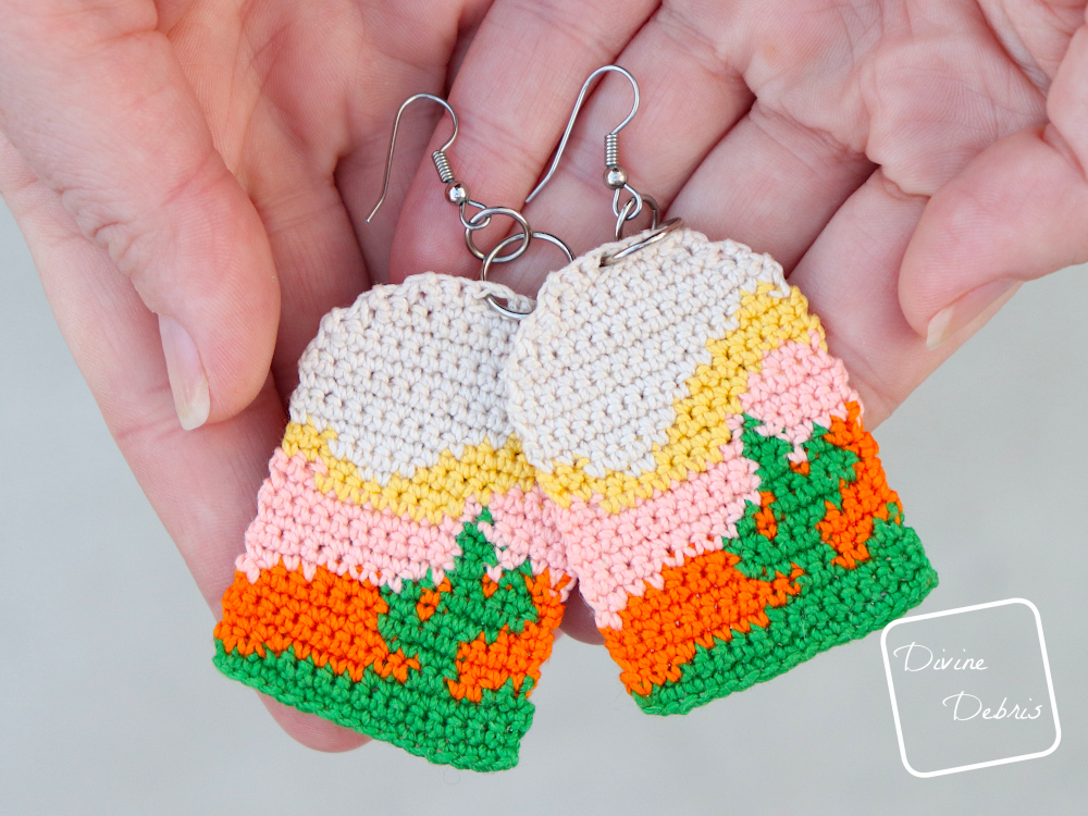 [Image description] Close up of a pair of white woman's hands holding the Sedona Cactus Crochet Earrings