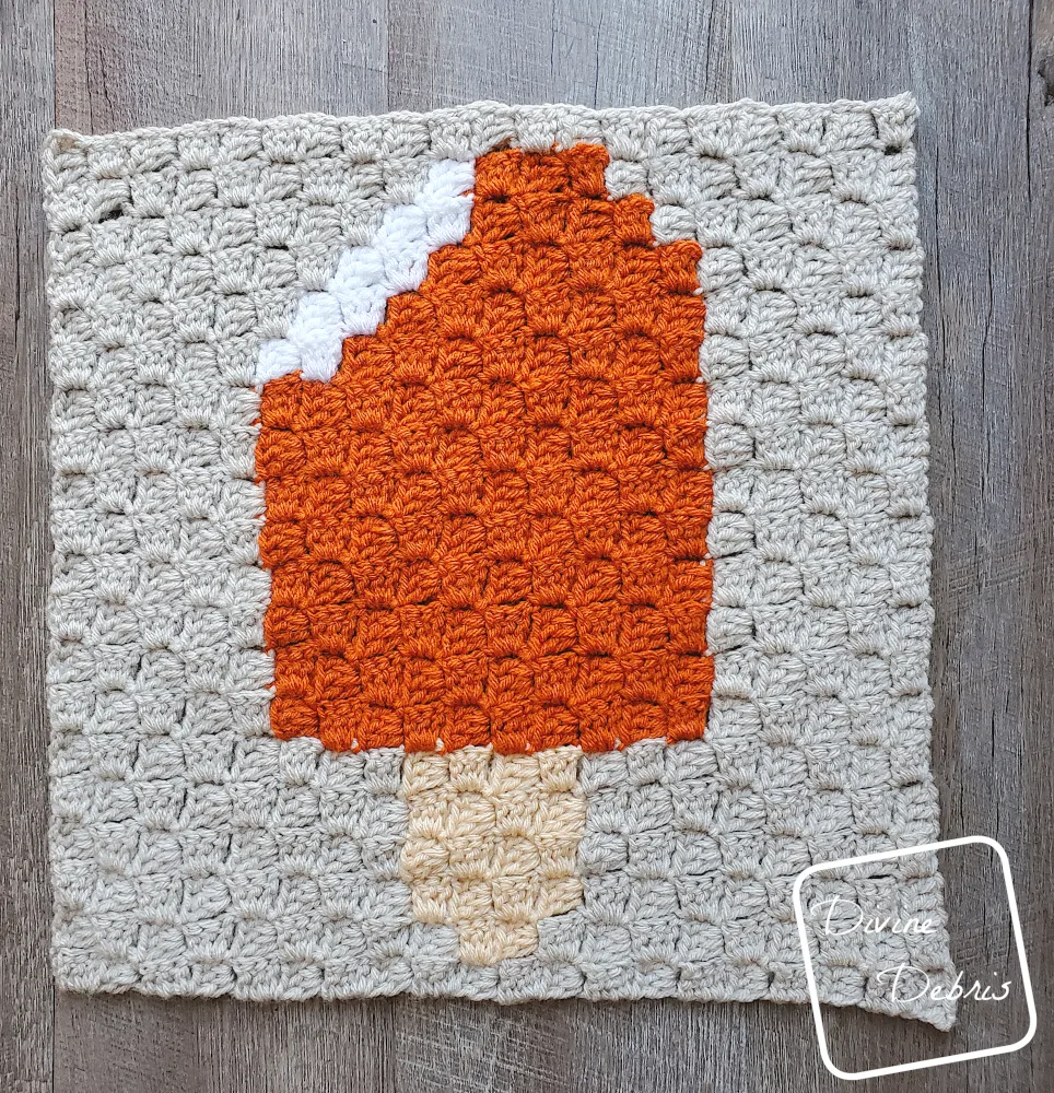 [Image description] Top down view of the Orange Creamsicle Afghan Square on a wood grain background