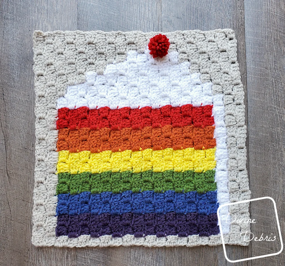 [Image description] C2C Rainbow Cake Afghan Square laying flat on a wood grain background