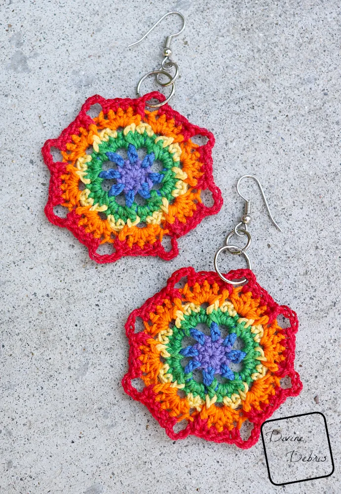 [Image description] top down view of the Flora Rainbow Earrings crochet pattern laying on a cement background.