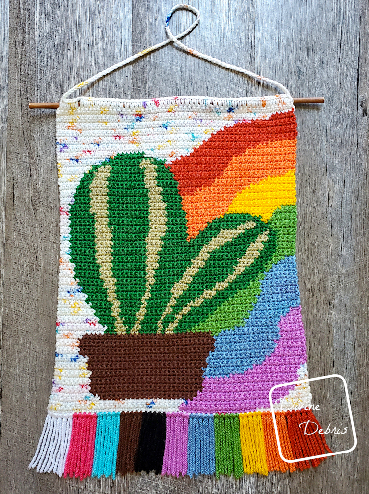 [Image description} Top down view of Rainbow Cactus Wall Hanging on a wood grain background.