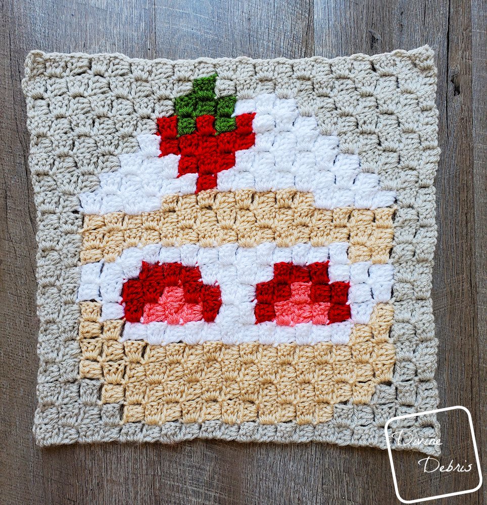 [Image description] C2C Strawberry Shortcake Afghan Square flat on a wood grain background.