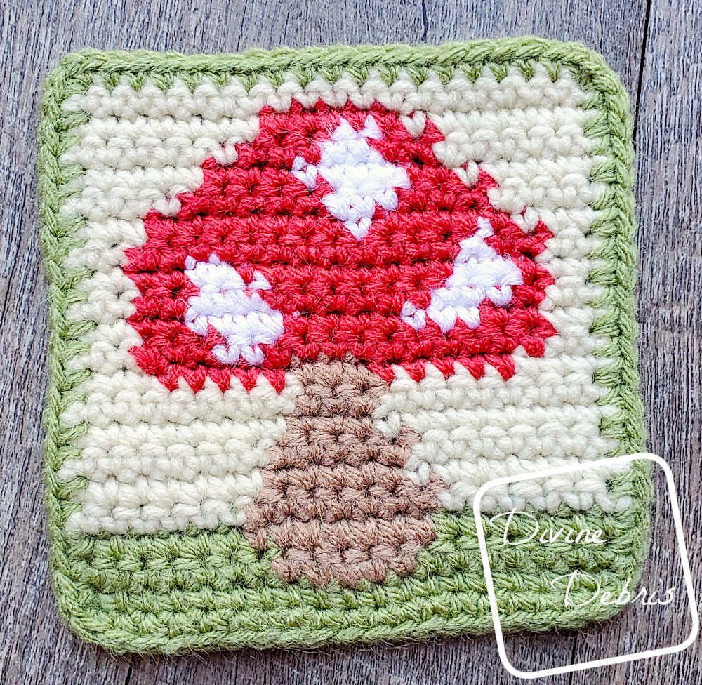 [Image description] Top down view of the Cute Mushroom Coaster crochet pattern, with cakes of yarn arranged around the left side