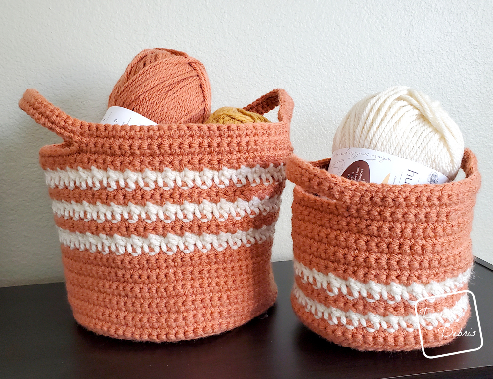 [Image description] The Cally Baskets Duo on a black shelf with a tan colored background with skeins of yarn in the baskets