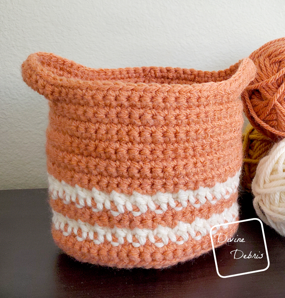 [Image description] The small version of the Cally Baskets Duo on a black shelf with a tan colored background and skeins of yarn on the right