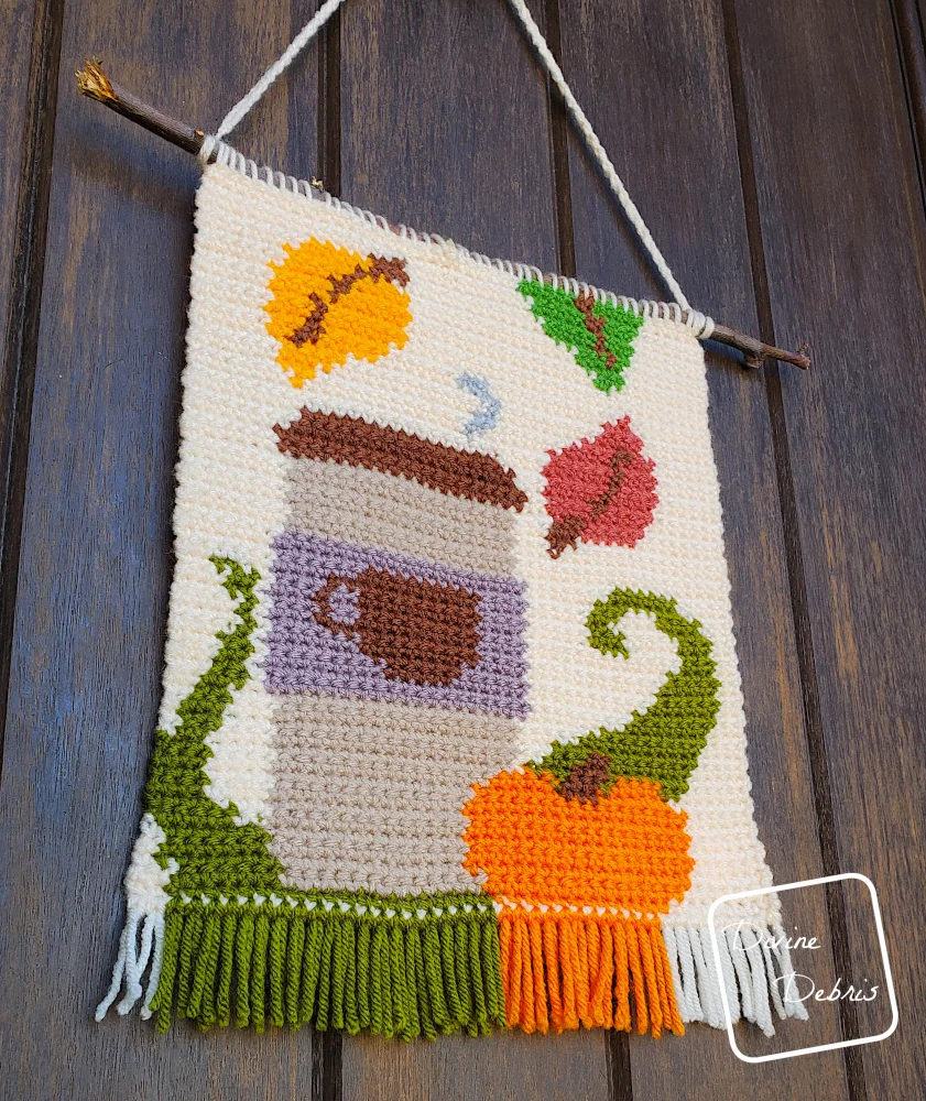 [Image description] A low angle photo of the Fall Coffee Wall Hanging against a wooden door