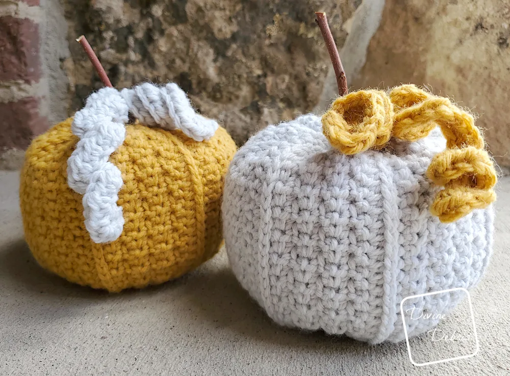 [Image description] 2 Keeley Pumpkins, one yellow and one gray, sitting on a cement ground against a brick wall