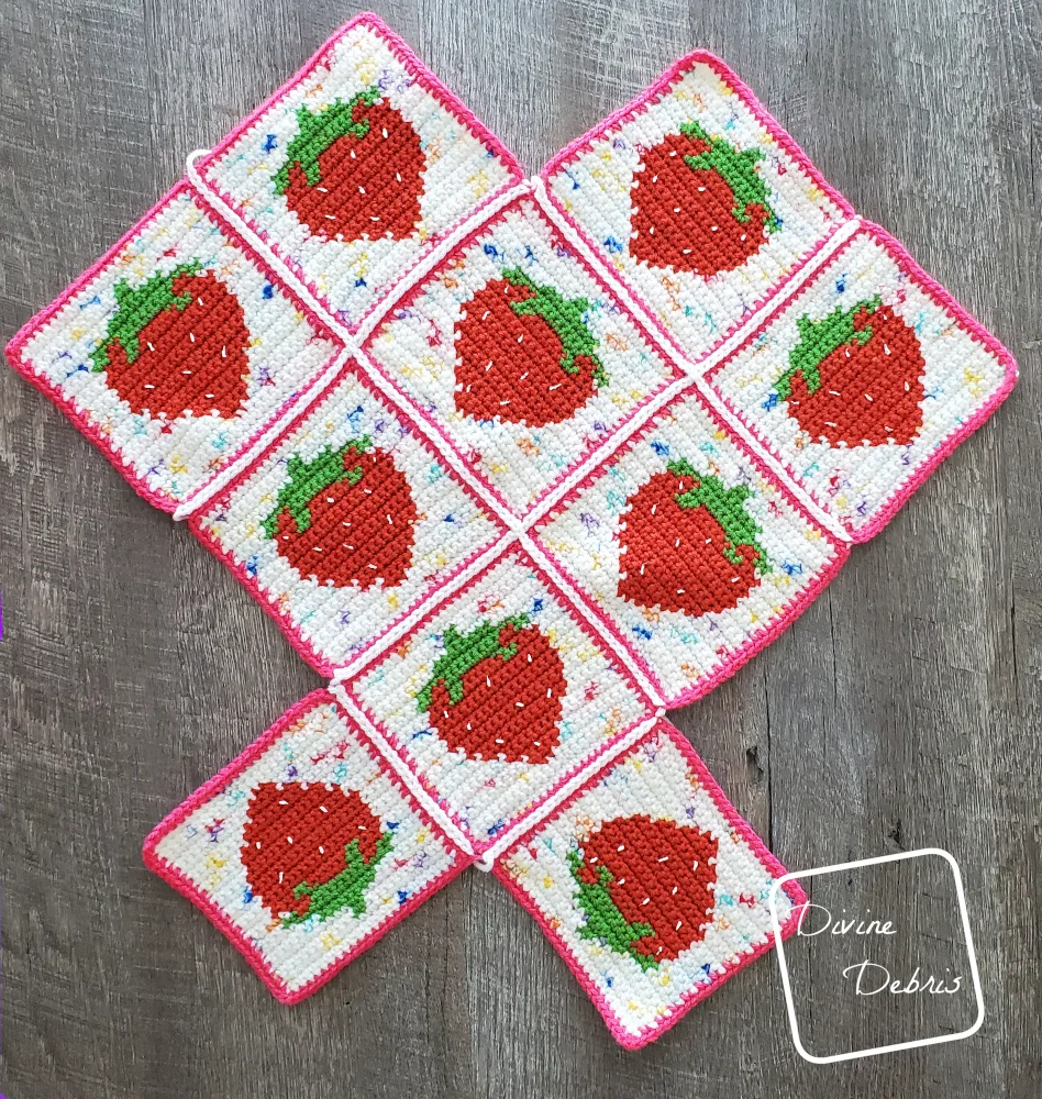 [Image description] Cute Strawberry Bag assembly photo 1 - all 10 squares are seamed and are laying on an fake wood background.