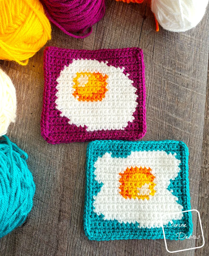 [Image description] Top down view of the Sunny Side Up Egg Squares, laying on a fake wood background with skeins of yarn along the top and left side of the photo.