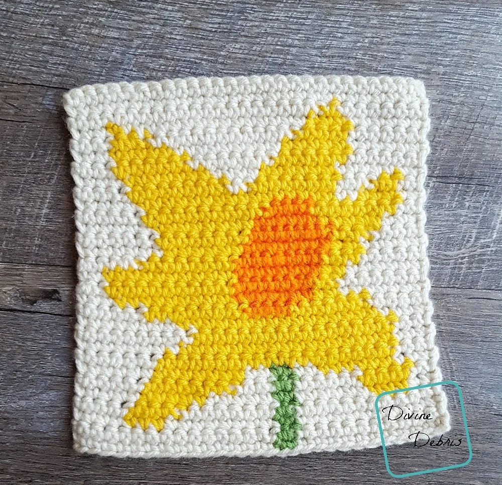 [Image description] top down view of the 8" Tapestry Daffodil Afghan Square on a wood grain background