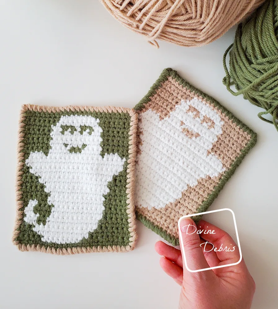 [Image description] Top down view of two Cute Ghost Coasters, a green and white one laying on top of a tan and white one, with a white woman's hand holding the bottom corner of the tan and white one. 