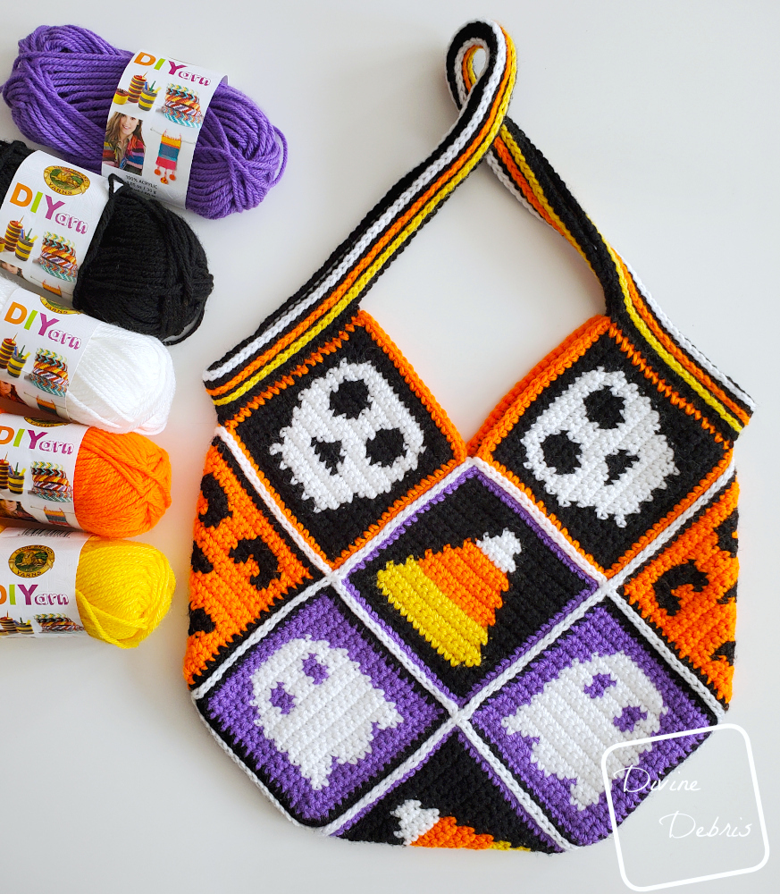 [Image description] The Patchwork Halloween Bag sits on a white background with skeins of yarn along the left side of the photo.