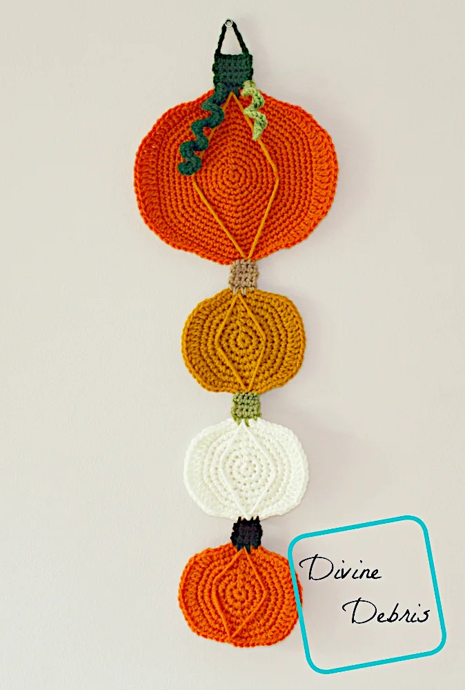 [image description} the Pumpkins Wall Decoration laying against a tan colored wall