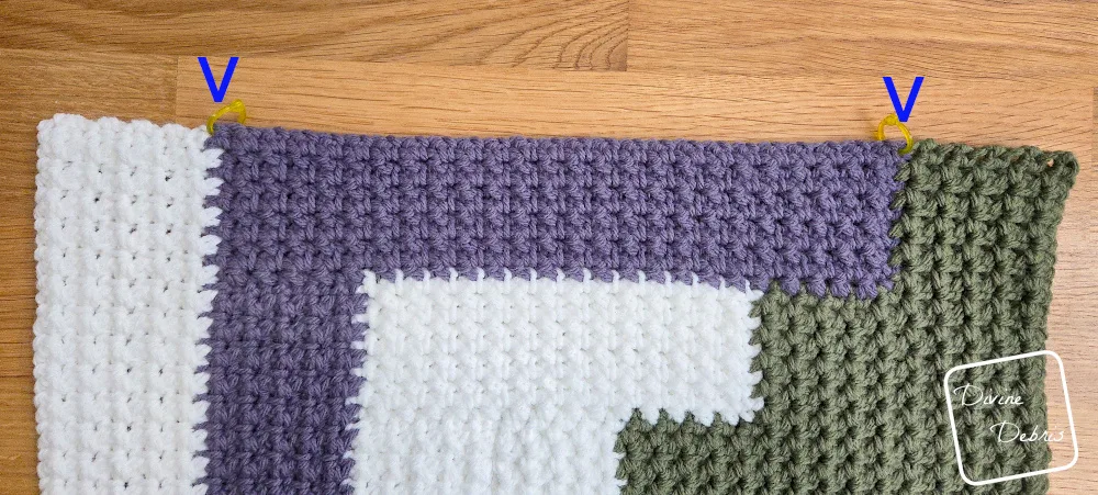 [Image description] Close up of the Mountain Log Cabin Blanket square with stitch markers and arrows on where to place the stitch markers to make the pattern easier to work.