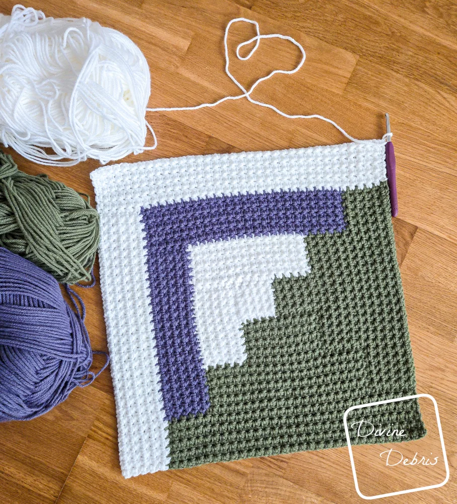 [Image description] Top down look of an unfinished Mountain Log Cabin Blanket crochet square with 3 skeins of yarn along the left side of the photo. 