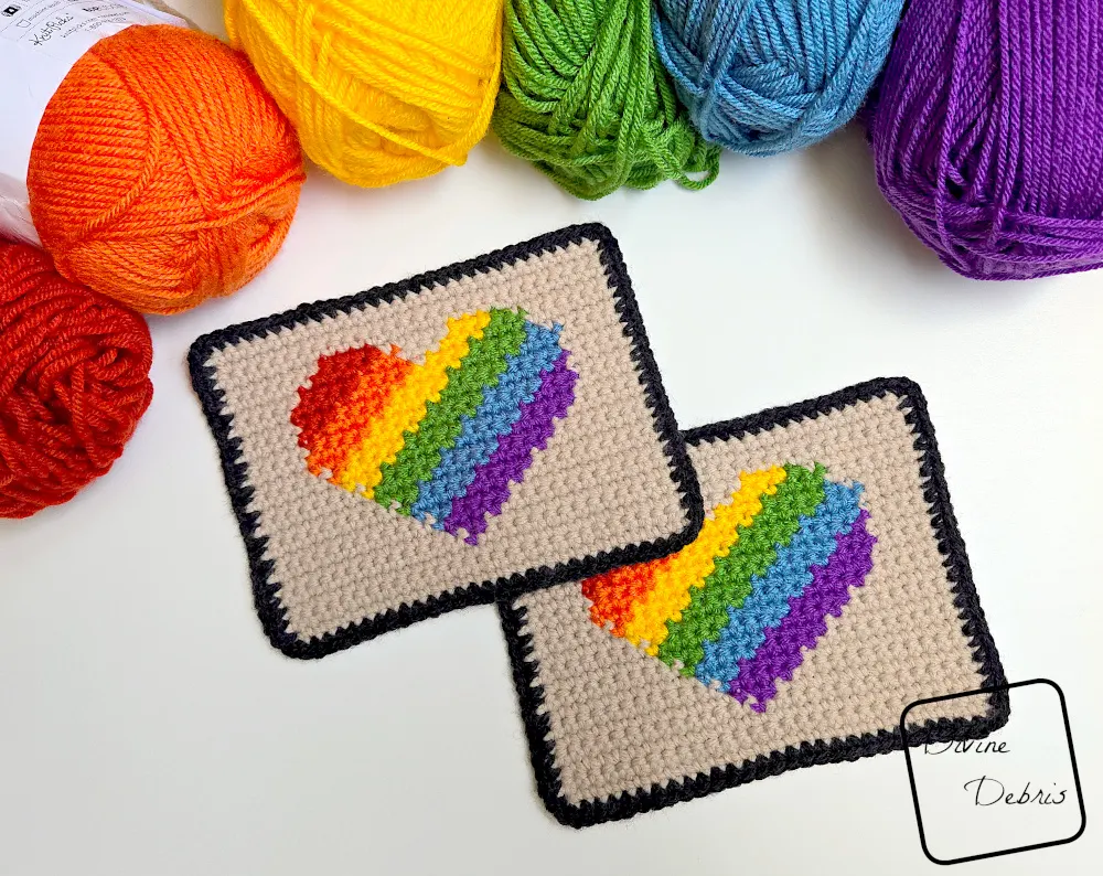 [Image description] 2 Rainbow Heart Coasters on a white background with skeins of yarn along top of the photo, arranged in a rainbow.