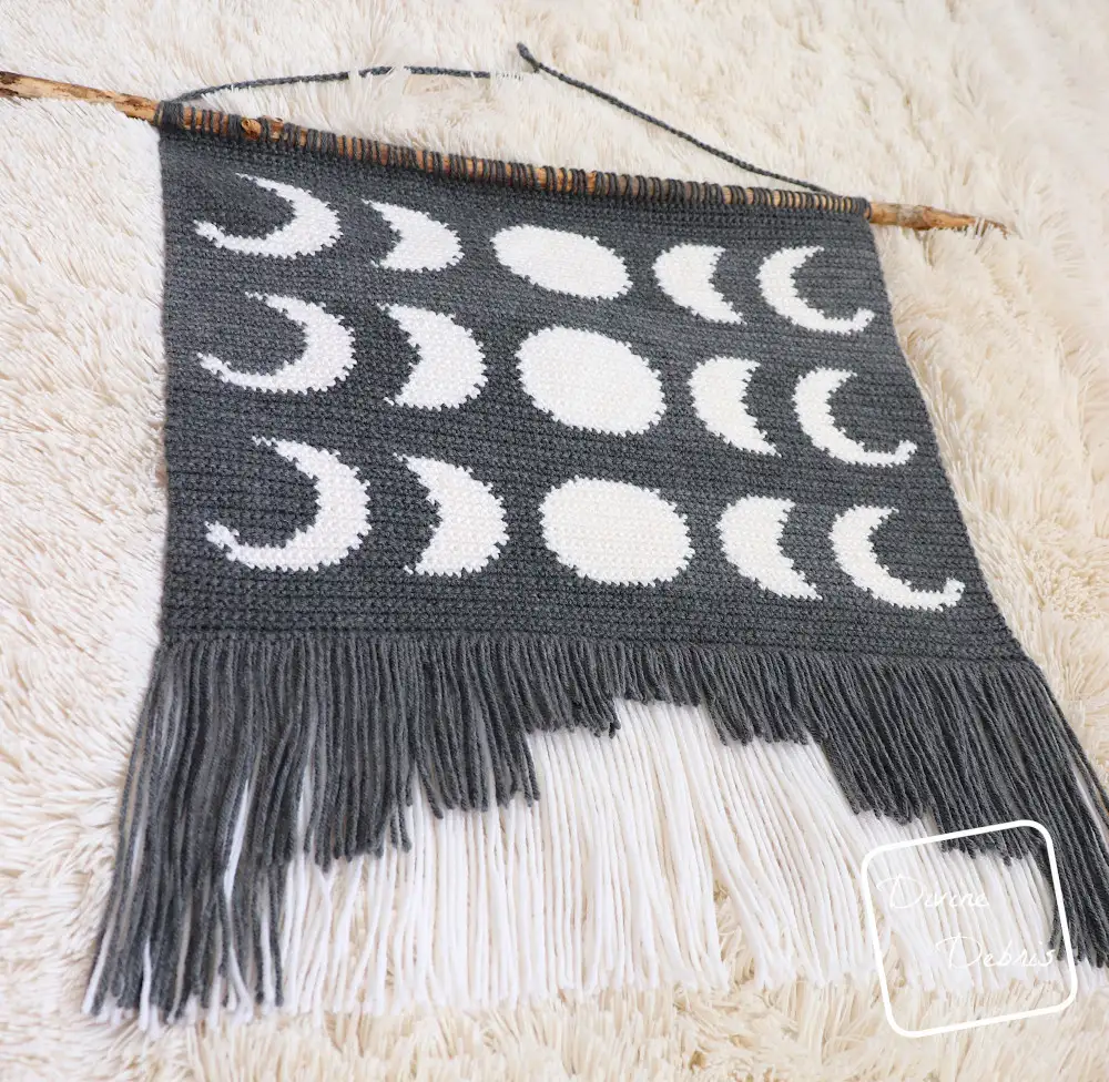 [Image description] A low angle from the left view of the Moon Phase Wall Hanging focusing on the fringe.