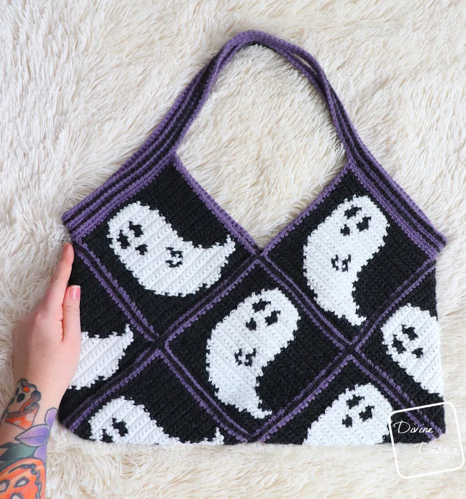 [Image description] Top down view of the Gwendoline Ghost Bag laying on a white faux fir background with a white woman's hand holding the left side.