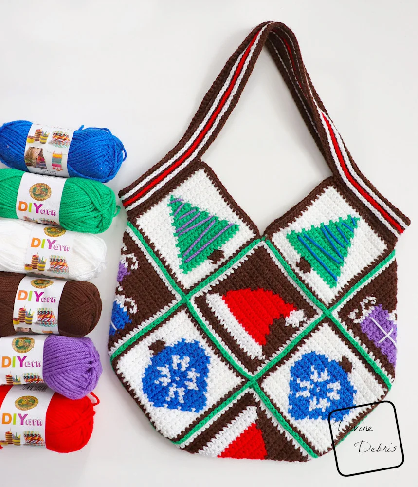 [Image description] The Patchwork Christmas Bag sits on a white background with skeins of yarn along the left side of the photo.