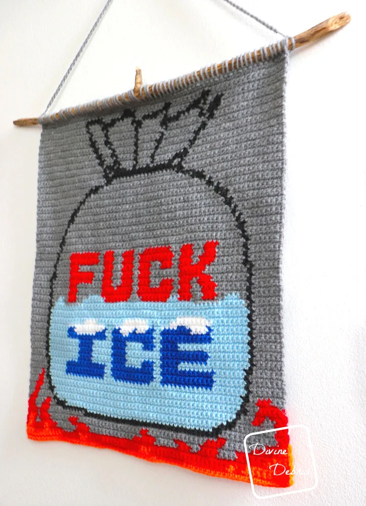 [Image description] The Fuck Ice Wall Hanging hangs on a white wall, photo taking from an angle.