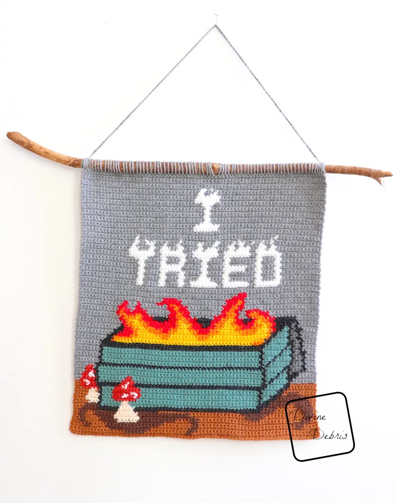 [Image description] The I Tried Dumpster Fire Wall Hanging hangs on a white wall.