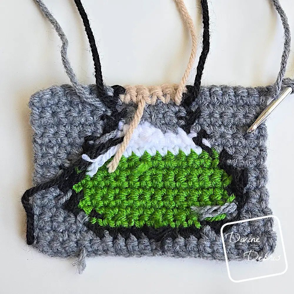[Image description] Top down look at an unfinished wrong side Cute Potions Coaster on a white background and strings coming from the top of the design.