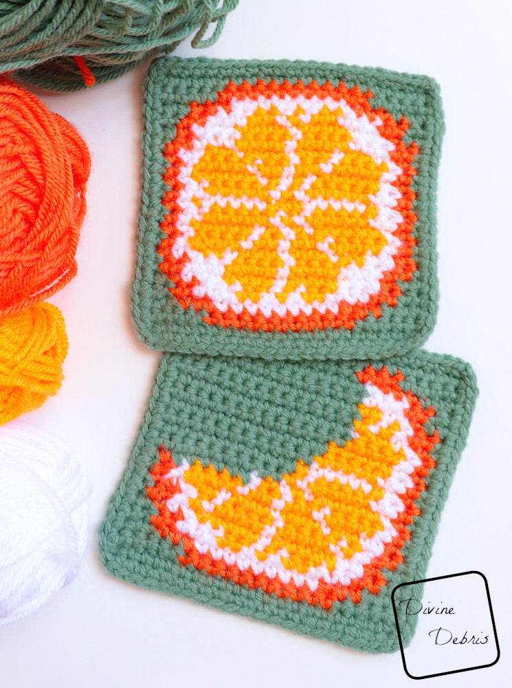 [Image description] Top down look at both Cute Oranges Coasters on a white background with skeins of yarn along the left side of the photo
